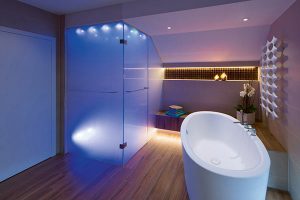Bad mit bodenenbener Dusche und freistehender Wanne im blauen Lichtspektrum.